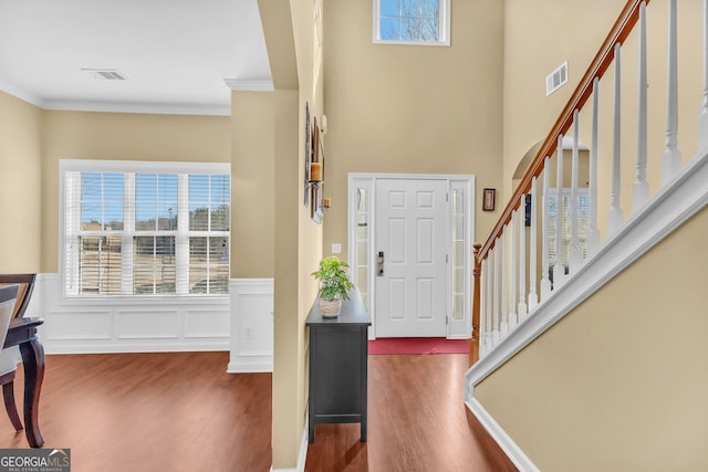 entrance foyer featuring dark wood-type flooring, ornamental molding, and plenty of natural light