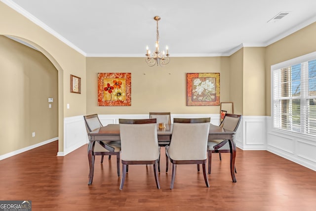 dining area with crown molding, dark hardwood / wood-style floors, and an inviting chandelier