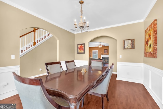 dining space featuring crown molding, dark wood-type flooring, and ceiling fan with notable chandelier