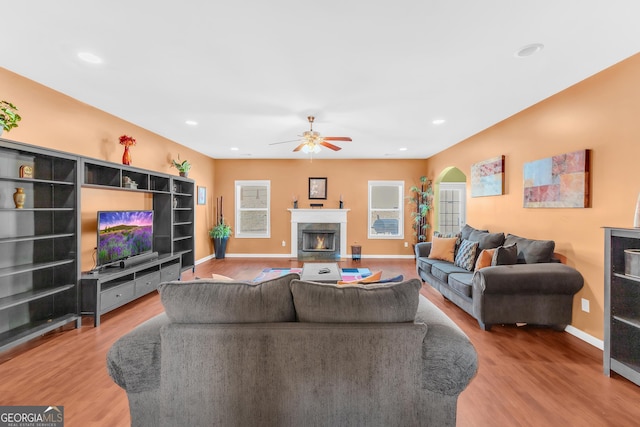 living room with ceiling fan, wood-type flooring, and a premium fireplace