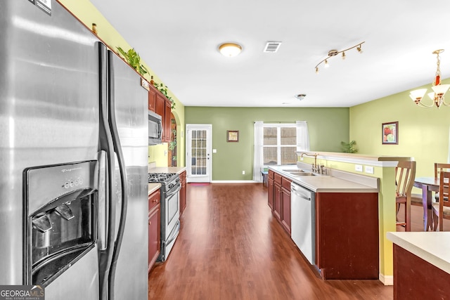 kitchen with hanging light fixtures, dark hardwood / wood-style floors, stainless steel appliances, and sink