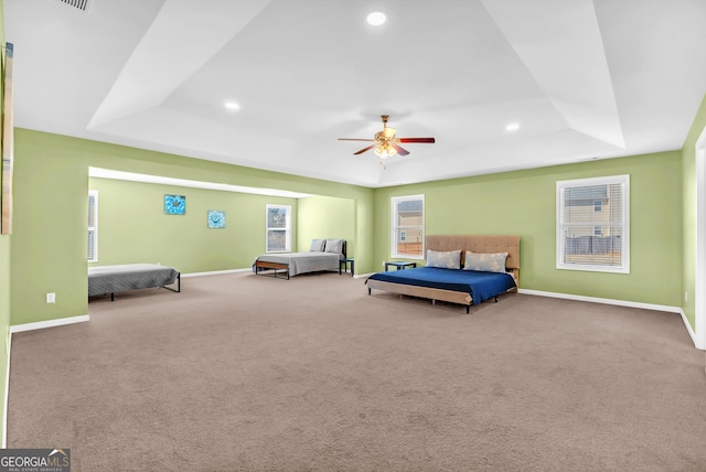 carpeted bedroom featuring a raised ceiling and ceiling fan