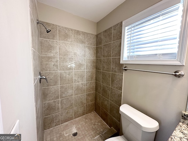 bathroom featuring tiled shower and toilet