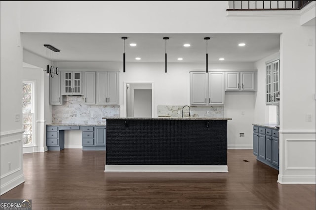 kitchen featuring gray cabinetry, kitchen peninsula, light stone counters, and decorative light fixtures