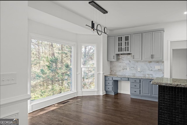 kitchen featuring hanging light fixtures, decorative backsplash, gray cabinets, and light stone countertops