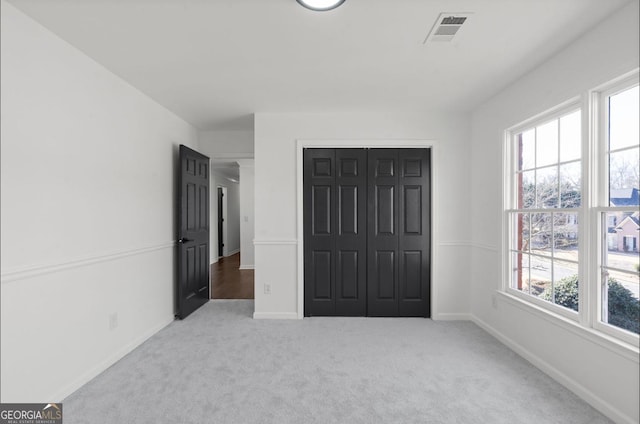 unfurnished bedroom with light colored carpet and a closet