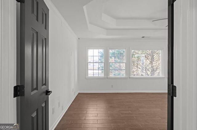 unfurnished room with crown molding, a tray ceiling, and dark hardwood / wood-style floors