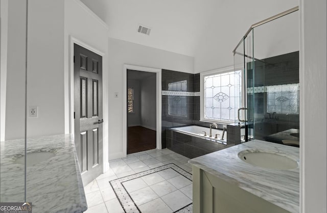 bathroom with tile patterned flooring, vanity, and tiled bath