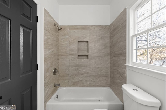 bathroom featuring toilet, tiled shower / bath combo, and a wealth of natural light