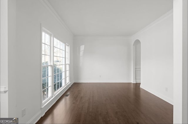 empty room featuring a healthy amount of sunlight, ornamental molding, and dark hardwood / wood-style floors