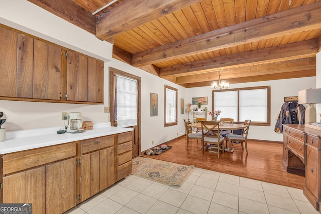 kitchen featuring decorative light fixtures, beamed ceiling, a chandelier, light tile patterned floors, and wooden ceiling