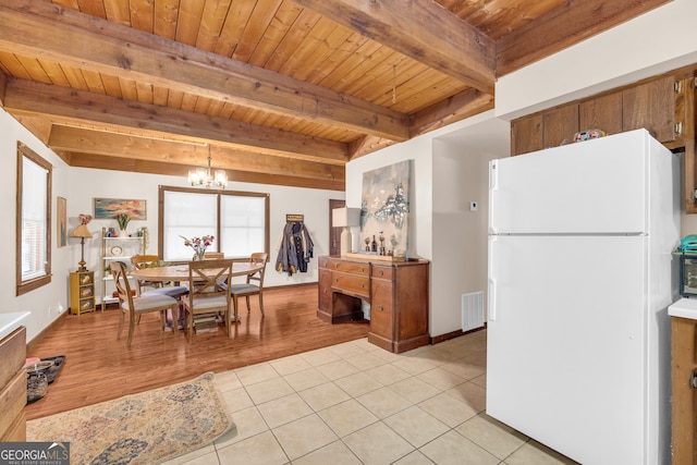 kitchen featuring an inviting chandelier, decorative light fixtures, white fridge, light tile patterned floors, and beam ceiling