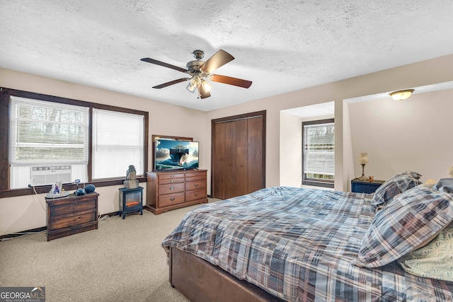 carpeted bedroom with a textured ceiling, a closet, and ceiling fan