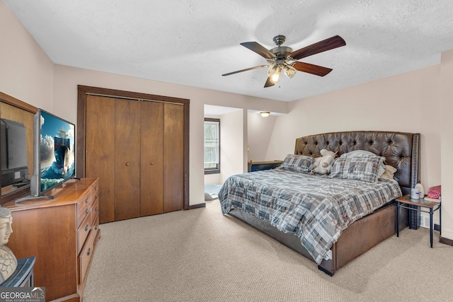 bedroom with a closet, ceiling fan, light colored carpet, and a textured ceiling