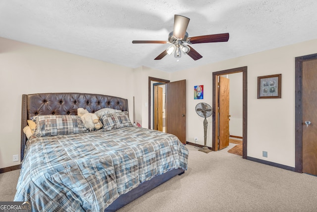 carpeted bedroom with a textured ceiling, ceiling fan, and ensuite bath