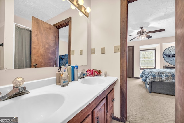 bathroom with ceiling fan, vanity, and a textured ceiling