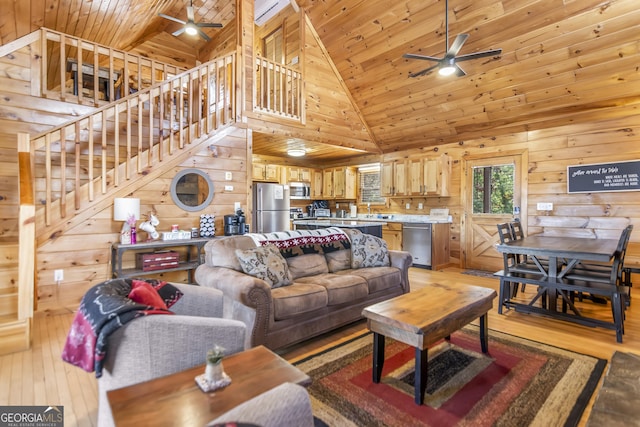 living room featuring ceiling fan, light hardwood / wood-style flooring, wood ceiling, and wood walls