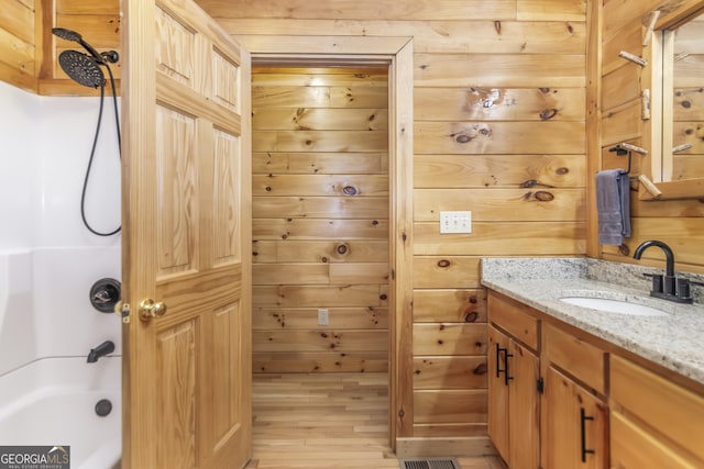 bathroom with vanity, bathing tub / shower combination, and wood walls