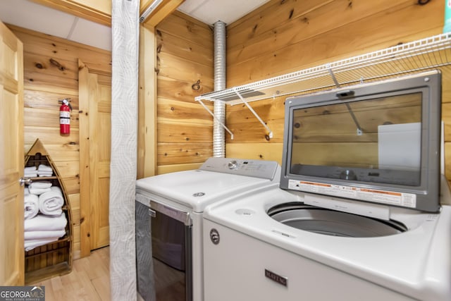 laundry area featuring light hardwood / wood-style flooring, washer and dryer, and wood walls