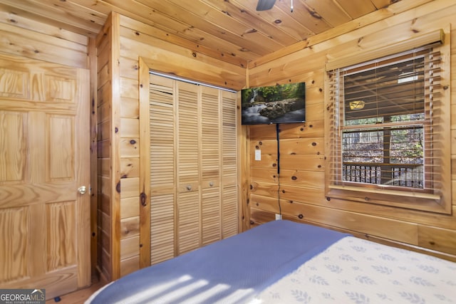 bedroom with wood ceiling, wooden walls, and a closet