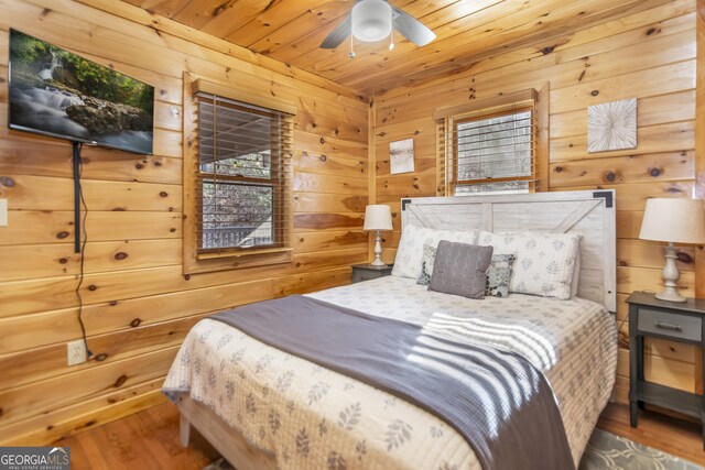 bedroom featuring hardwood / wood-style floors, wood ceiling, wooden walls, and ceiling fan