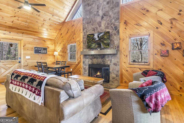 living room featuring wooden walls, a wealth of natural light, a fireplace, and light hardwood / wood-style floors