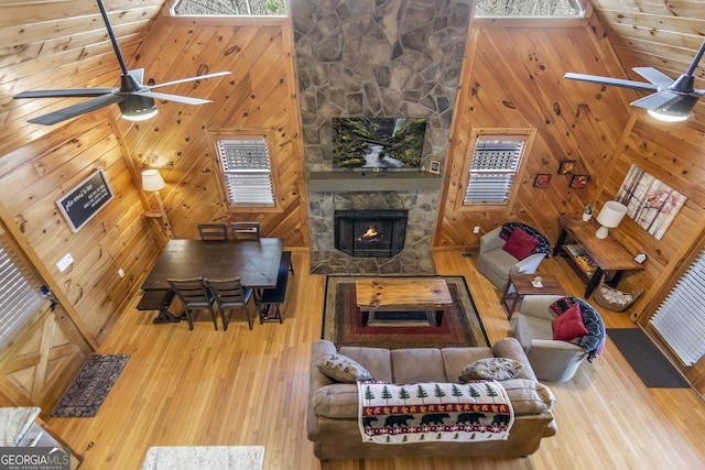 living room featuring ceiling fan, wooden walls, hardwood / wood-style floors, and a fireplace