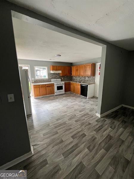 4402 Highland Rd, Decatur, GA 30035 - kitchen featuring white appliances, wood finished floors, backsplash, brown cabinetry, and light countertops