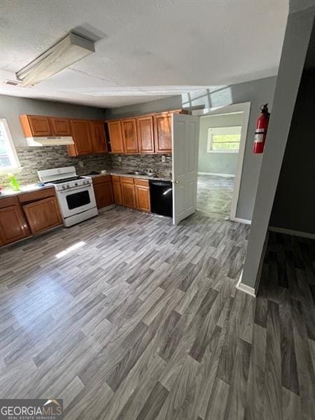 4402 Highland Rd, Decatur, GA 30035 - kitchen featuring white gas range, black dishwasher, light wood-style floors, decorative backsplash, and a textured ceiling