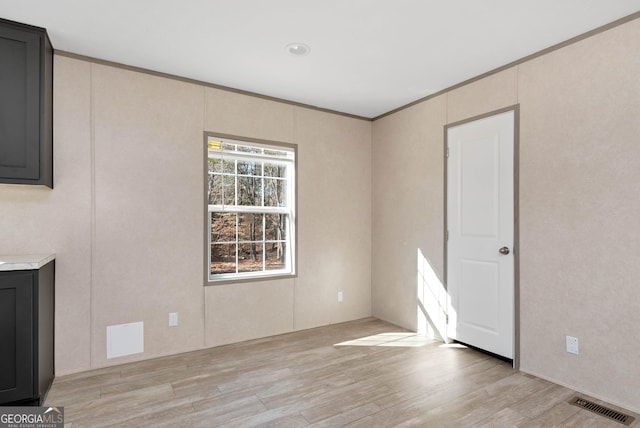 empty room featuring ornamental molding and light wood-type flooring