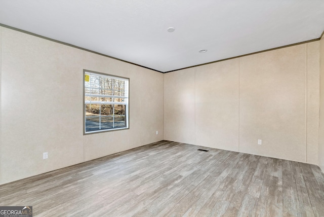 spare room with crown molding and light hardwood / wood-style flooring