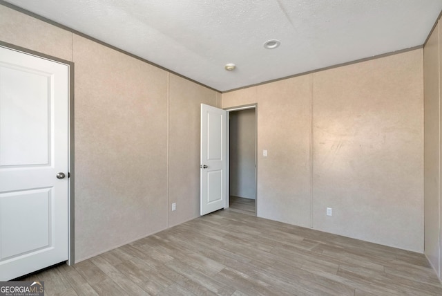 spare room with ornamental molding, a textured ceiling, and light hardwood / wood-style flooring