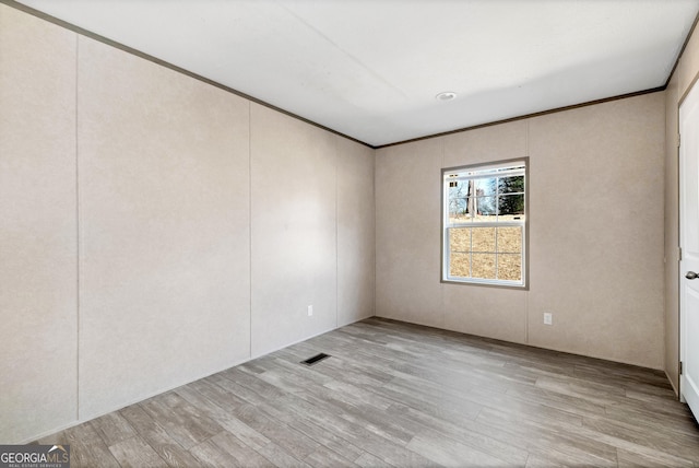 empty room with ornamental molding and light wood-type flooring