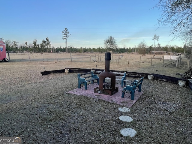 view of yard featuring a rural view, a fire pit, and a patio