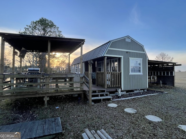 back house at dusk with a wooden deck and an outdoor structure