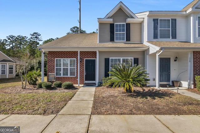 view of front of home featuring a shingled roof and brick siding