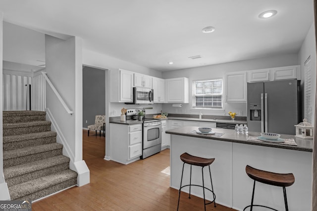 172 Sonata Cir, Pooler, GA 31322 - kitchen with stainless steel appliances, a breakfast bar area, white cabinetry, dark countertops, and recessed lighting