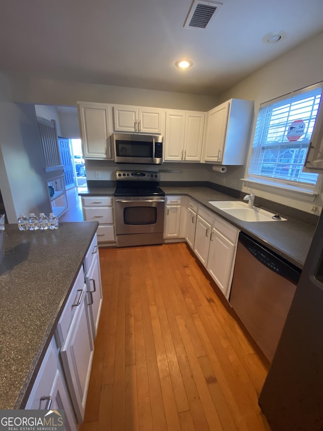 172 Sonata Cir, Pooler, GA 31322 - kitchen with appliances with stainless steel finishes, white cabinets, light wood-style floors, dark stone counters, and recessed lighting