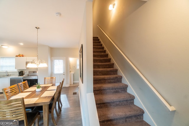 stairway with sink, a notable chandelier, and hardwood / wood-style flooring