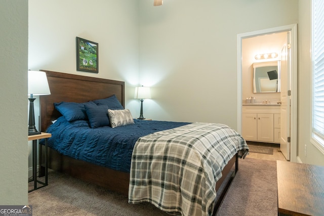 bedroom with ensuite bath and light colored carpet