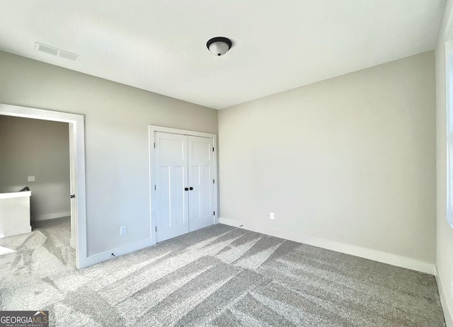 unfurnished bedroom with light colored carpet and a closet