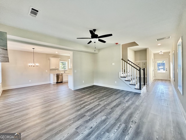 unfurnished living room featuring hardwood / wood-style flooring, a wealth of natural light, sink, and ceiling fan with notable chandelier