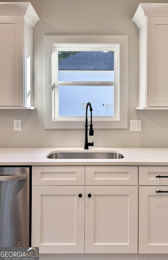 kitchen with dishwasher, sink, and white cabinets