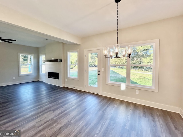 unfurnished dining area with dark hardwood / wood-style floors and ceiling fan with notable chandelier