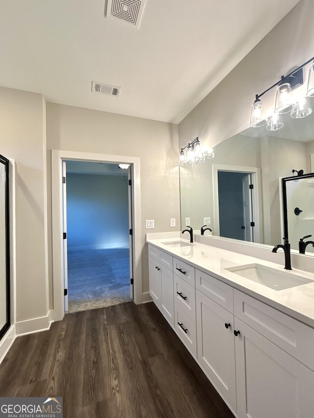 bathroom with hardwood / wood-style flooring, vanity, and a shower with door