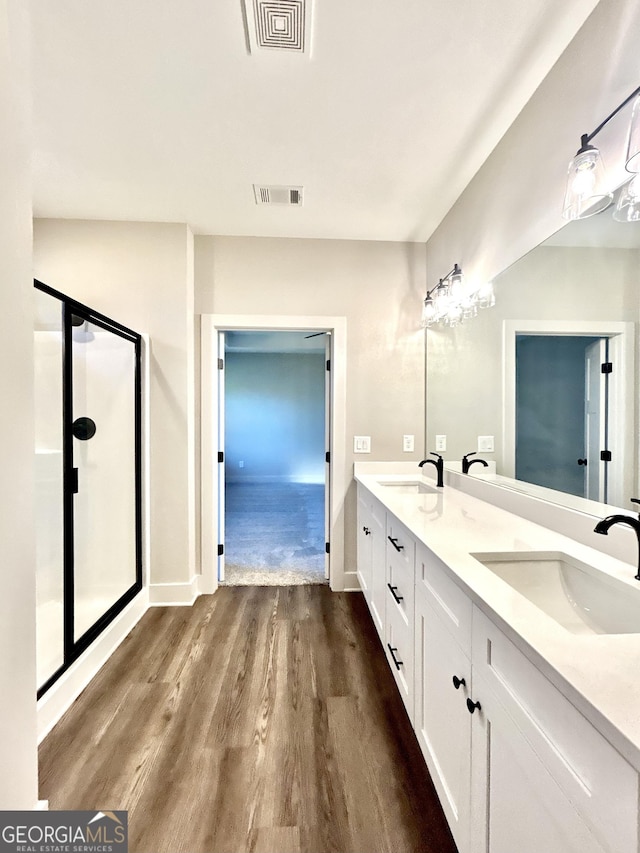 bathroom featuring wood-type flooring, a shower with shower door, and vanity