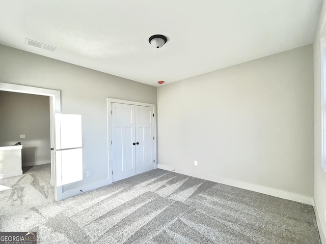 unfurnished bedroom featuring light colored carpet and a closet