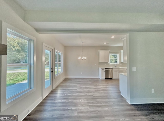 unfurnished dining area with a healthy amount of sunlight, a chandelier, and light hardwood / wood-style floors