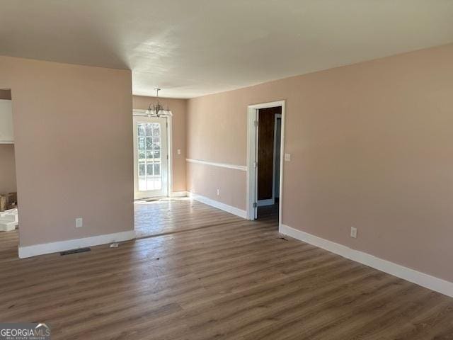 empty room featuring an inviting chandelier and dark hardwood / wood-style floors