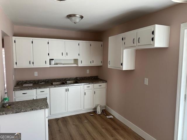 kitchen featuring dark stone countertops, dark hardwood / wood-style flooring, and white cabinets